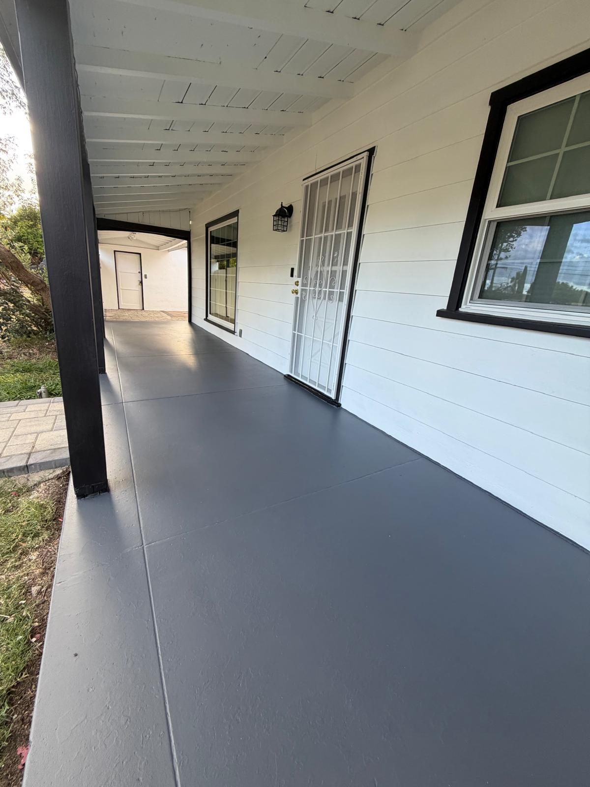 Covered porch with a coated floor, white siding, and black trim