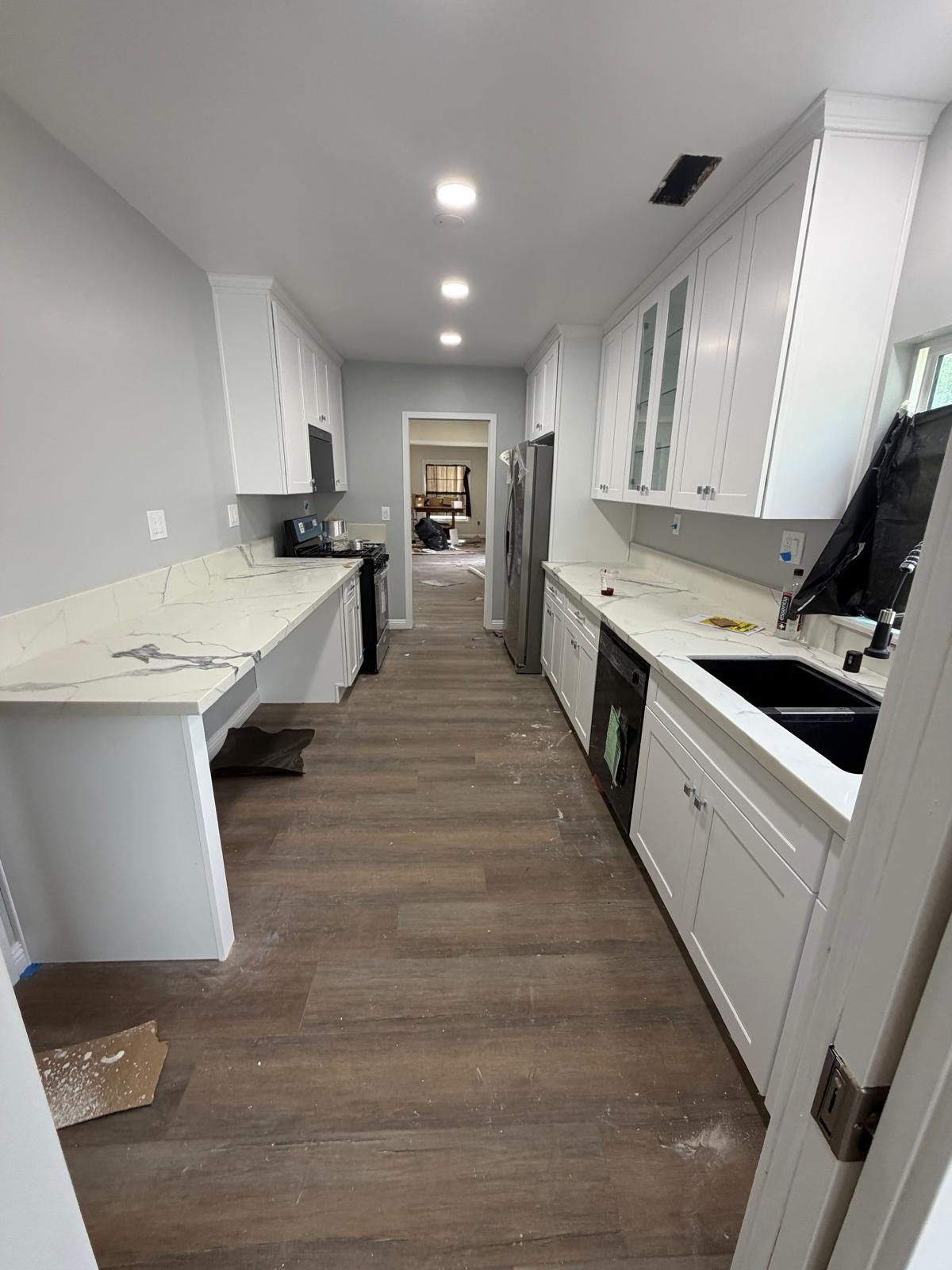 Galley kitchen with white cabinets and marble-look counters during install